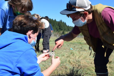 An instructor points to an oyster shell held by a student